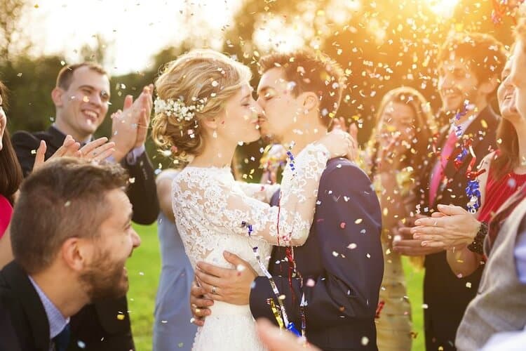 just married couple kissing while guests throw confetti